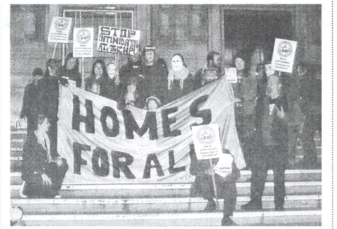 An archive newspaper photograph of campaigners on town-hall steps behind a hand-made "Homes for All" banner.